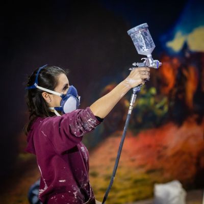 Student wearing mask and using a paint spray
